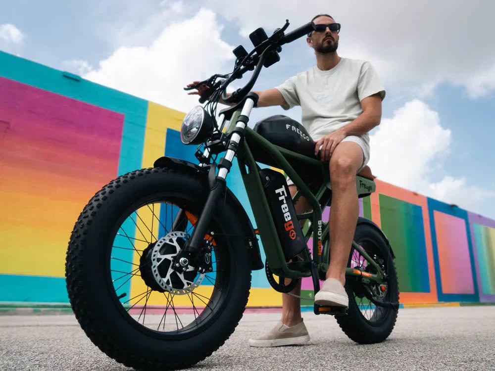 A man sitting on a Freego Flash F3 Pro against the colorful wall happy for learning about eBike classes explained in our community