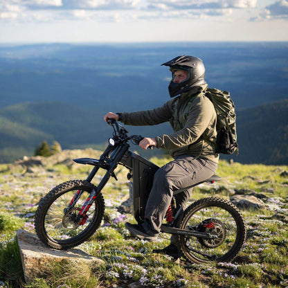 Person riding a Freego X2 Pro dirt ebike on a mountain with a scenic view in the background